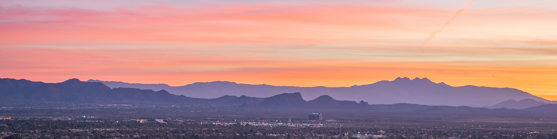 A cityscape at sunset with mountains in the background.
