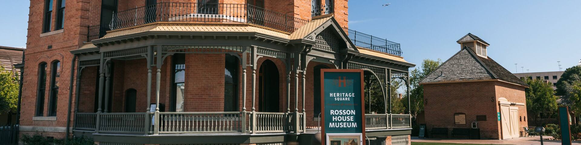 A historic house museum with a prominent porch and a signboard.