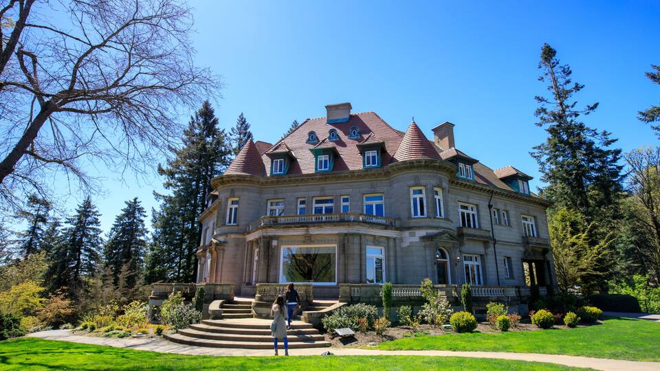 A large, historic building with a prominent turret and a well-manicured garden.