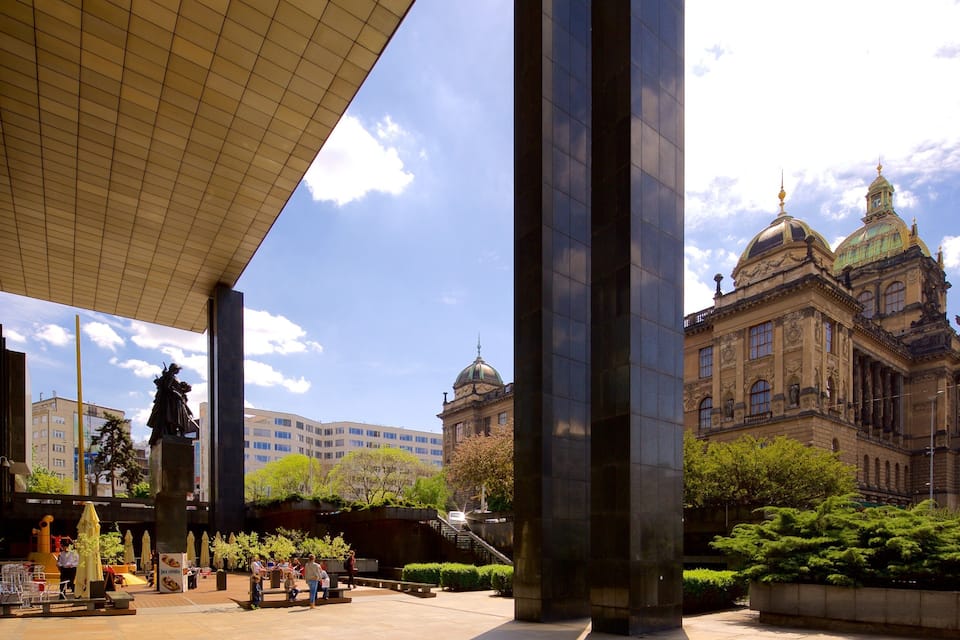 A plaza with a statue, a large building with a dome, and a covered area with columns.
