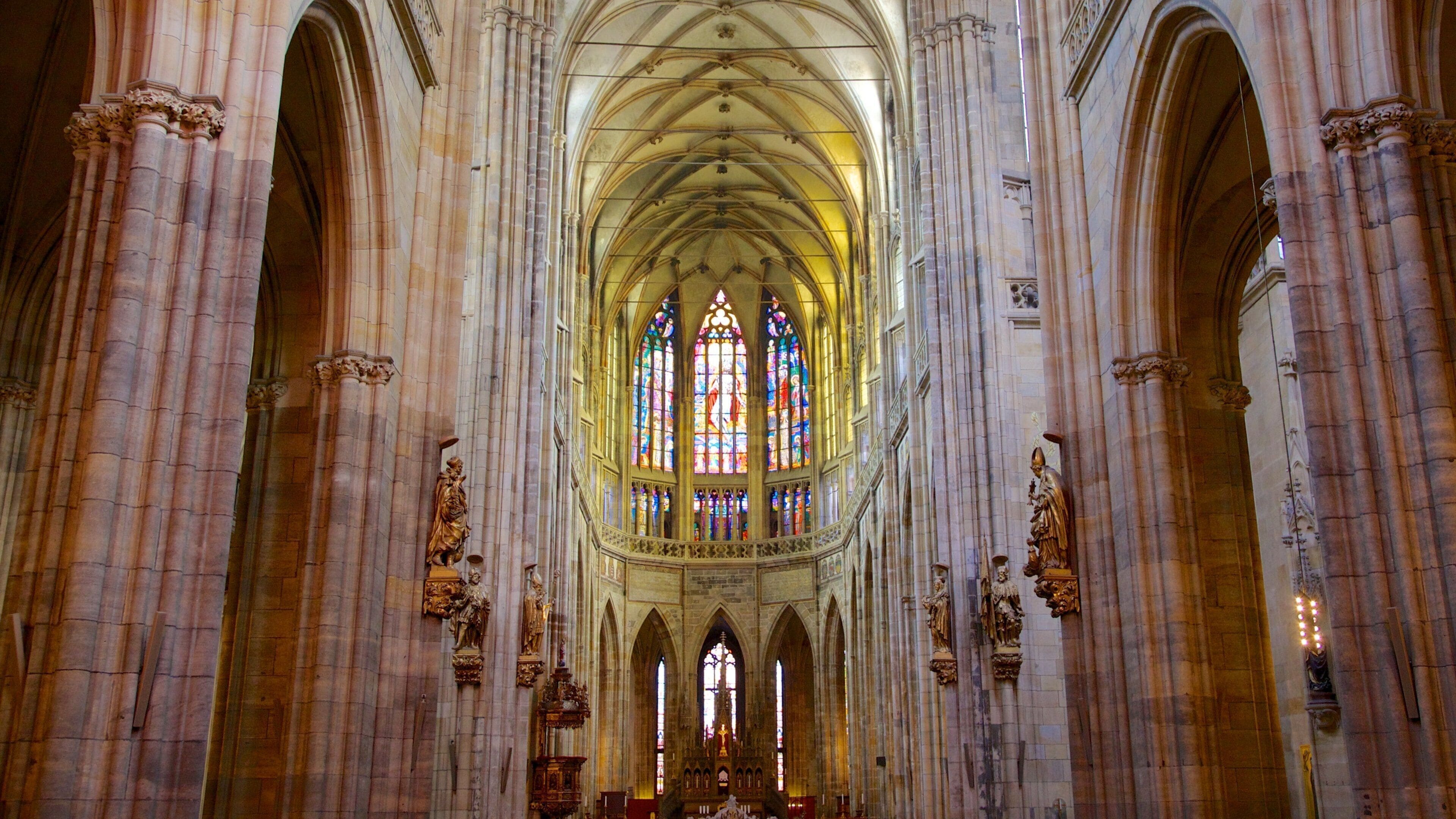 A cathedral interior with tall arched ceilings, stained glass windows, and ornate statues.