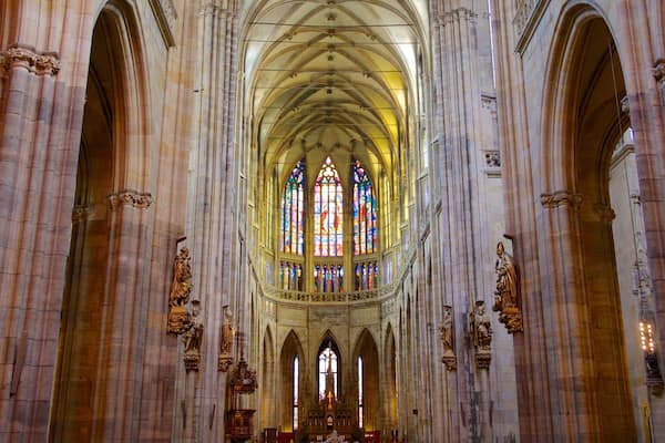 A cathedral interior with tall arched ceilings, stained glass windows, and ornate statues.