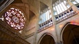 Interior de una catedral con amplios vitrales, techos abovedados y detalladas esculturas de piedra.