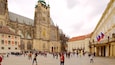 A historic square with a prominent cathedral featuring intricate Gothic architecture and a clock tower.