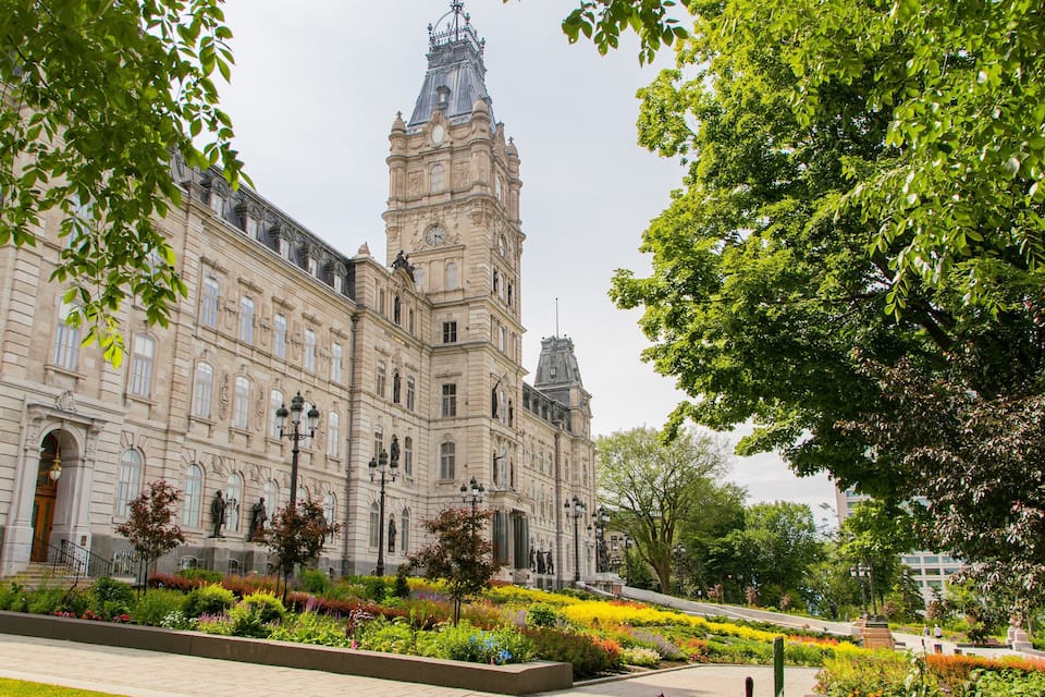 A historic building with a clock tower, surrounded by lush greenery and a well-maintained garden.