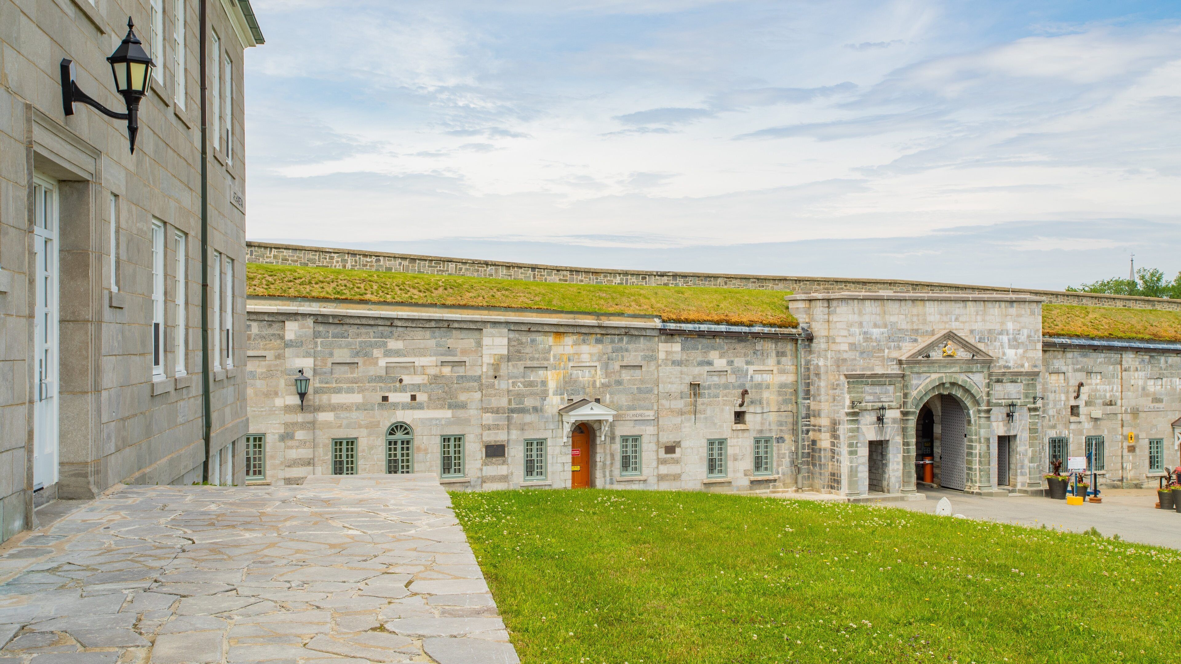 A historic stone building with green windows and a grassy courtyard.