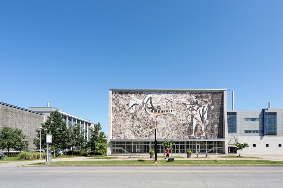 A modern building with a large mural of a dinosaur and a person riding a bicycle.