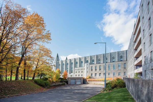 Un grand bâtiment à l’architecture moderne, entouré d’arbres aux feuilles d’automne.