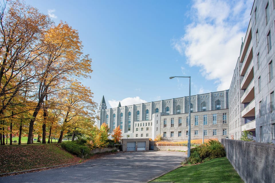 Ein großes Gebäude im modernen Architekturstil, umgeben von Bäumen mit Herbstlaub.