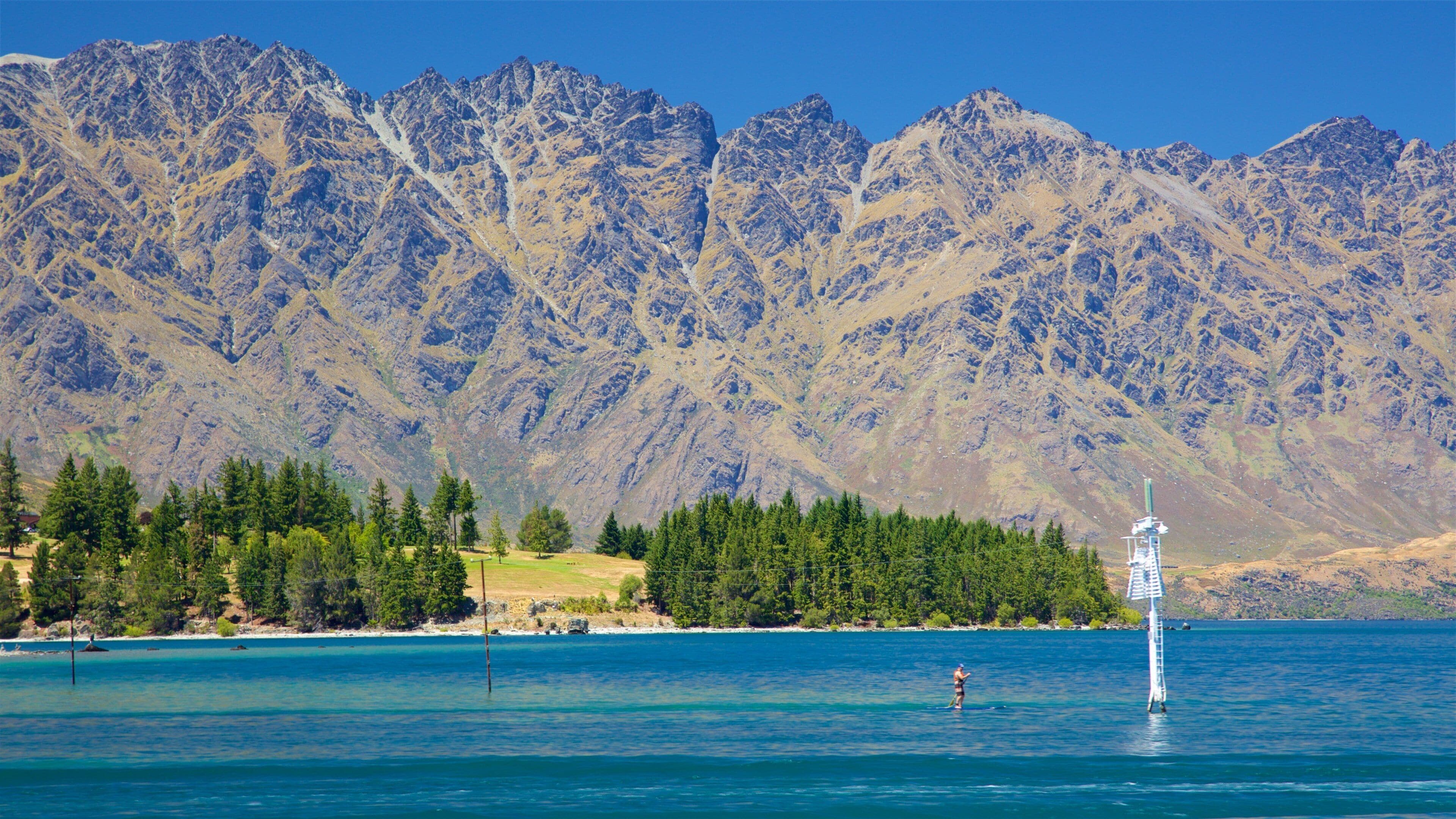 A lake with clear blue water, surrounded by a forest and mountains.