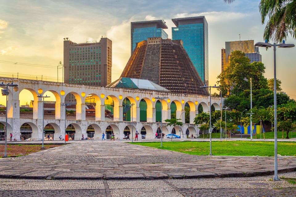 A historic building with arches and a modern skyscraper in the background.