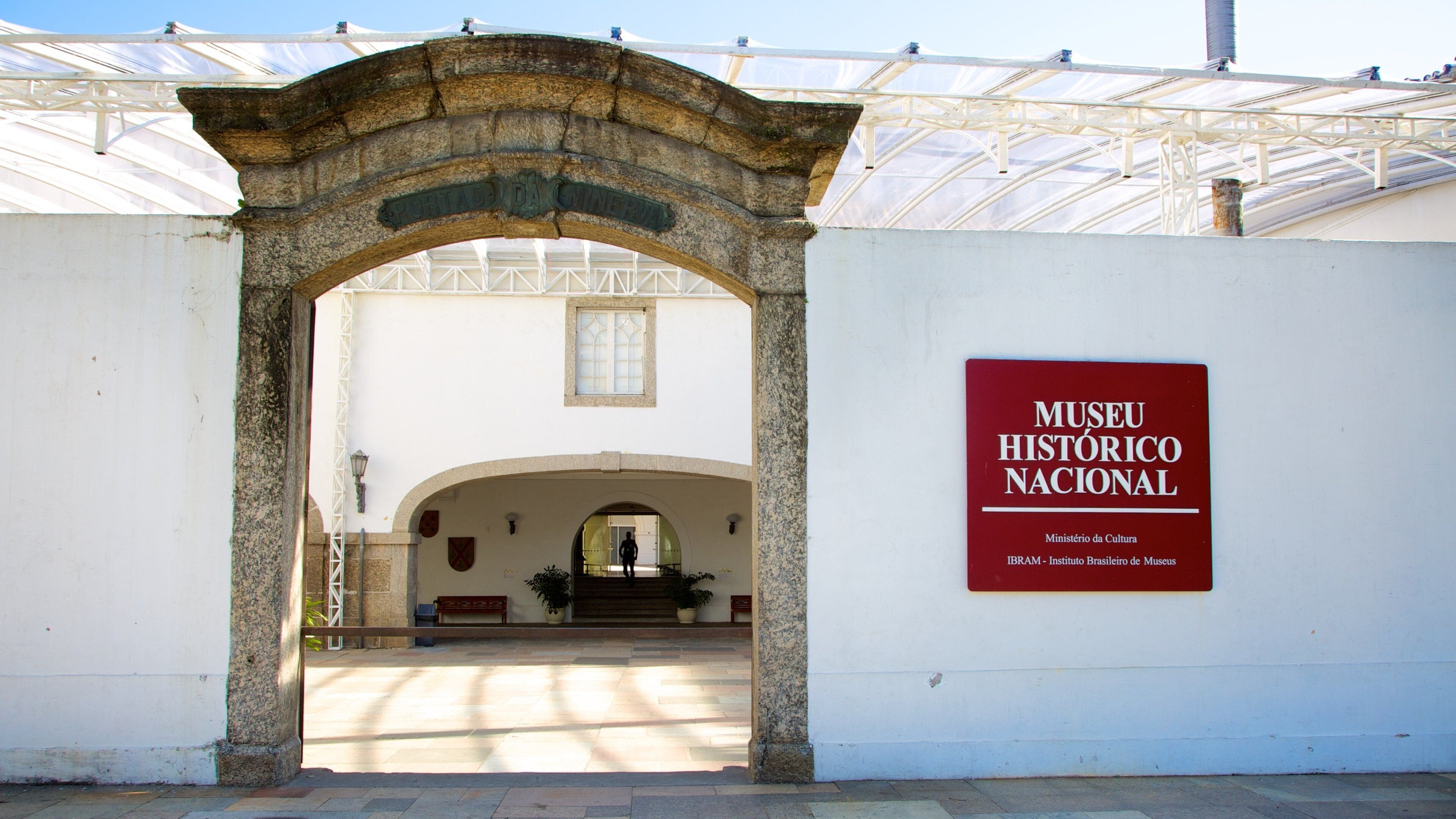 Entrada do Museu Histórico Nacional, com um arco de pedra e uma placa na parede.