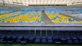 An empty stadium with blue and yellow seats and a central walkway.