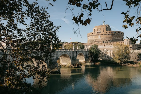 A historic building with a round tower, a stone bridge, and a river.