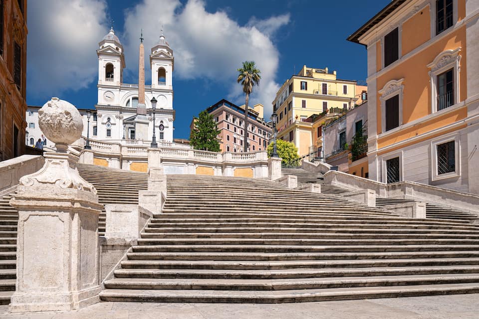 A grand staircase leading to a historic church with twin bell towers, surrounded by classic European architecture.