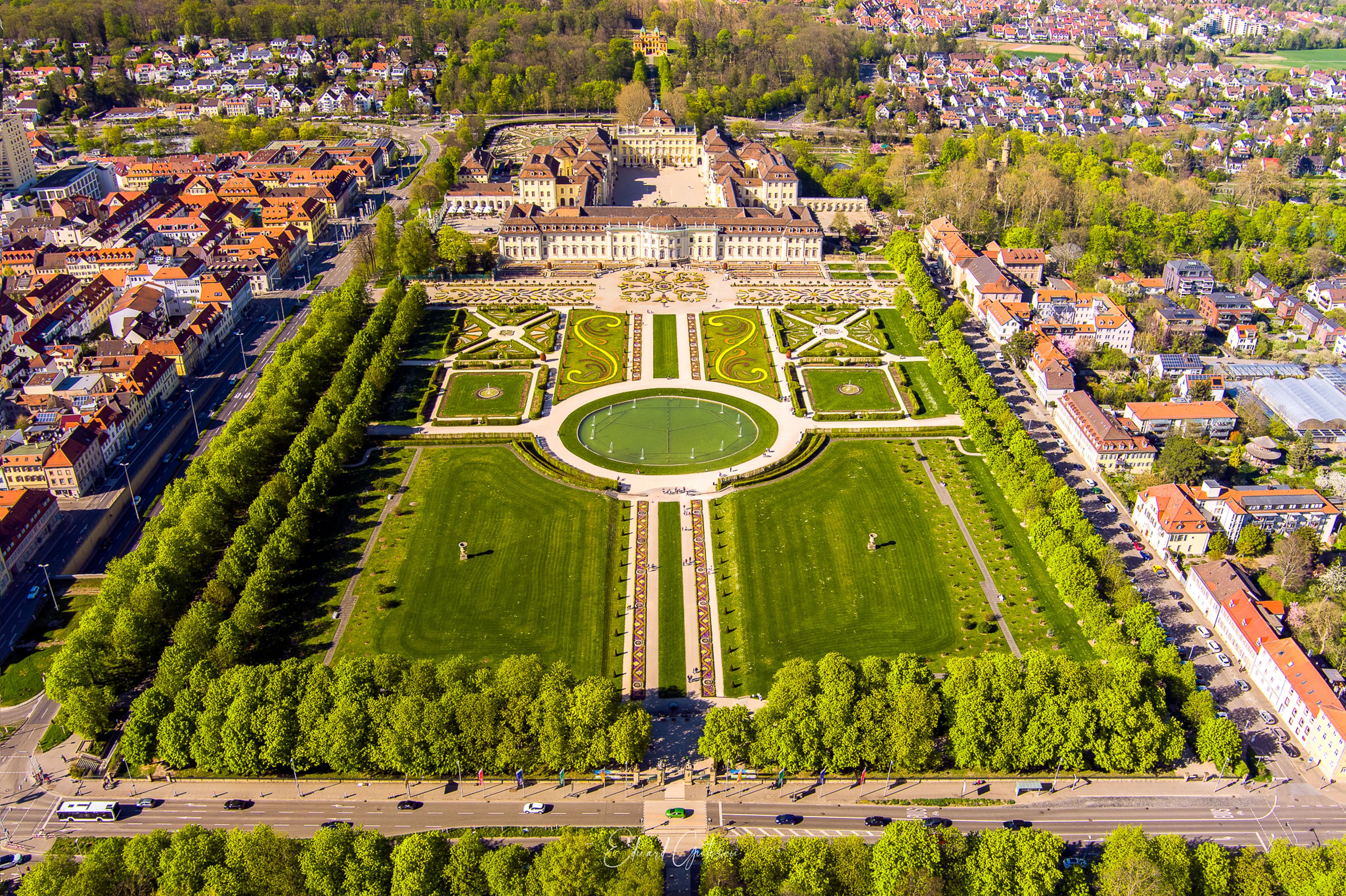 An aerial view of a historic palace with a large formal garden, surrounded by residential buildings.