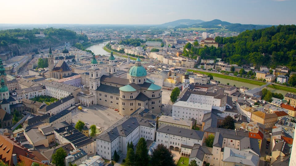 A cityscape with a prominent church with green domes, a river running through the city, and surrounding greenery.