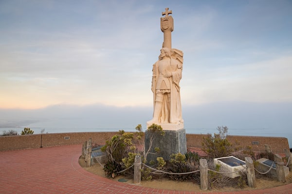 Cabrillo National Monument featuring a sunset, religious aspects and a statue or sculpture