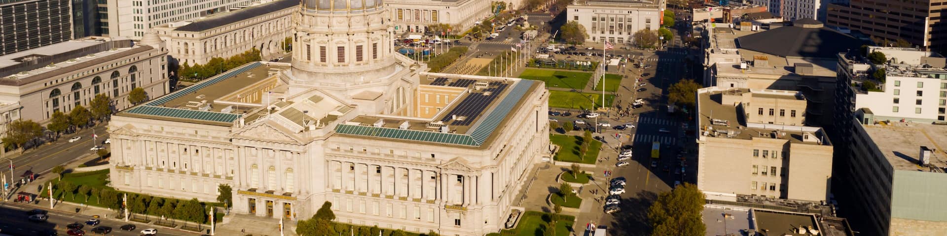 Un paisaje urbano con un edificio histórico destacado que tiene una cúpula, rodeado de rascacielos modernos y un cielo despejado.