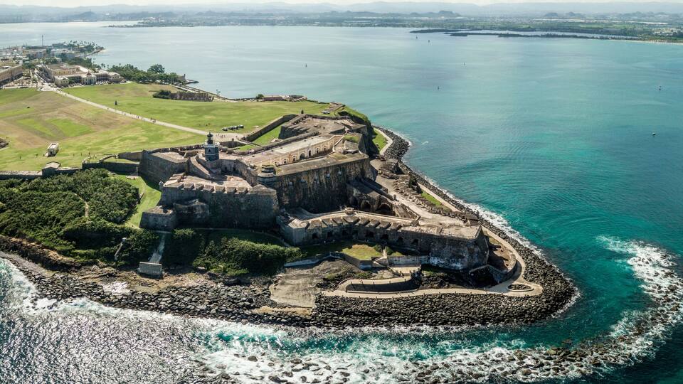 A coastal fortification with a surrounding moat and a grassy area.