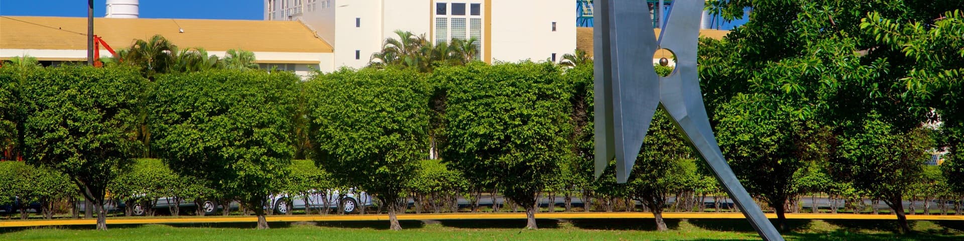 A Bacardi building with a tall chimney, surrounded by trees and a modern sculpture.