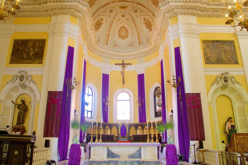 L'intérieur d'une église avec un crucifix, un autel et des statues.