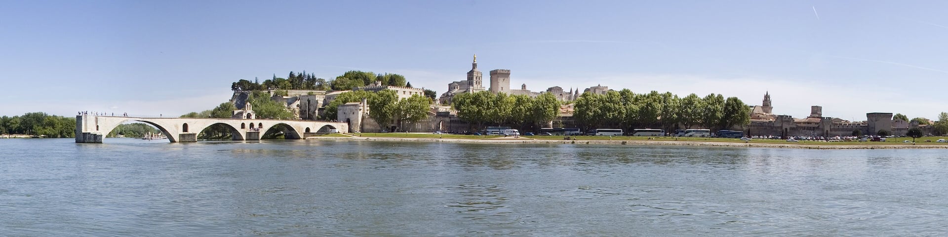 A historic bridge over a river, with a castle and towers in the background.