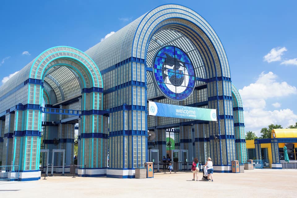 Un edifici gran i modern amb una combinació de colors blau i blanc, que destaca per un finestra circular i un cartell de 'Welcome'.