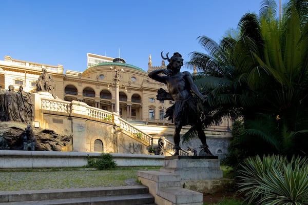 A statue of a man holding a sword in front of a building with columns and a staircase.