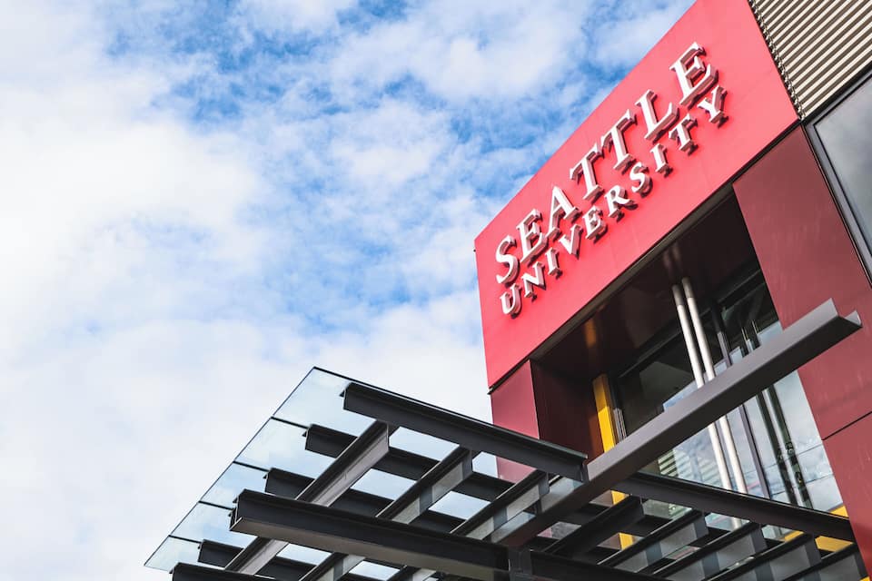 The Seattle University building with a red facade and a glass entrance.