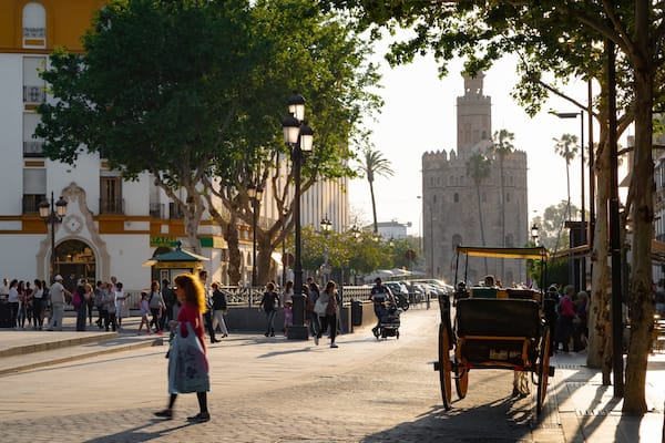 Torre del Oro Watchtower which includes a sunset and street scenes as well as an individual femail