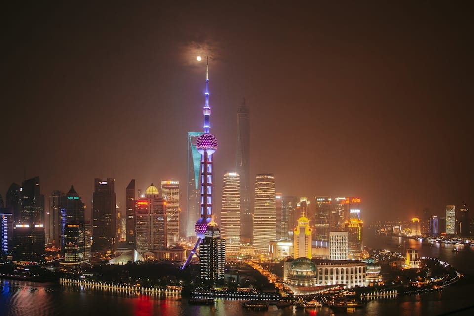 A city skyline at night with illuminated buildings and a prominent tower with a spherical structure at its top.