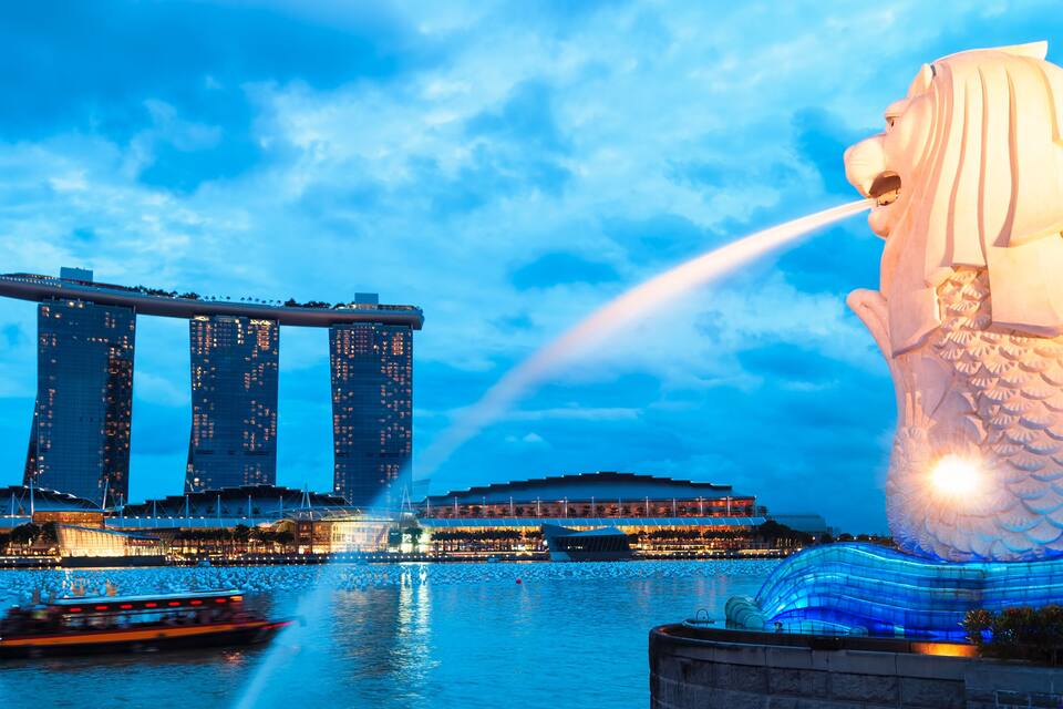 O hotel Marina Bay Sands, um edifício moderno e imponente com três torres, e a emblemática estátua Merlion com água jorrando da boca.