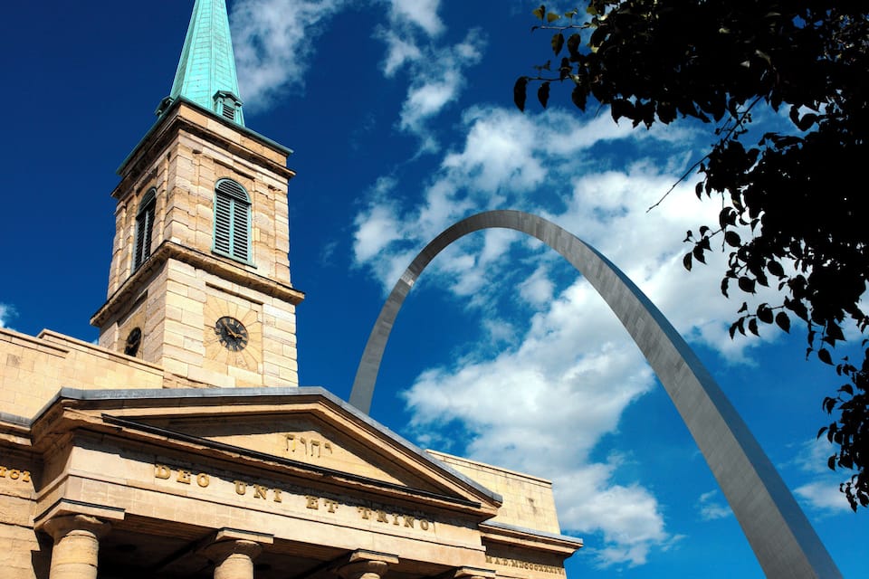 Uma igreja com uma torre do relógio e um grande arco ao fundo.