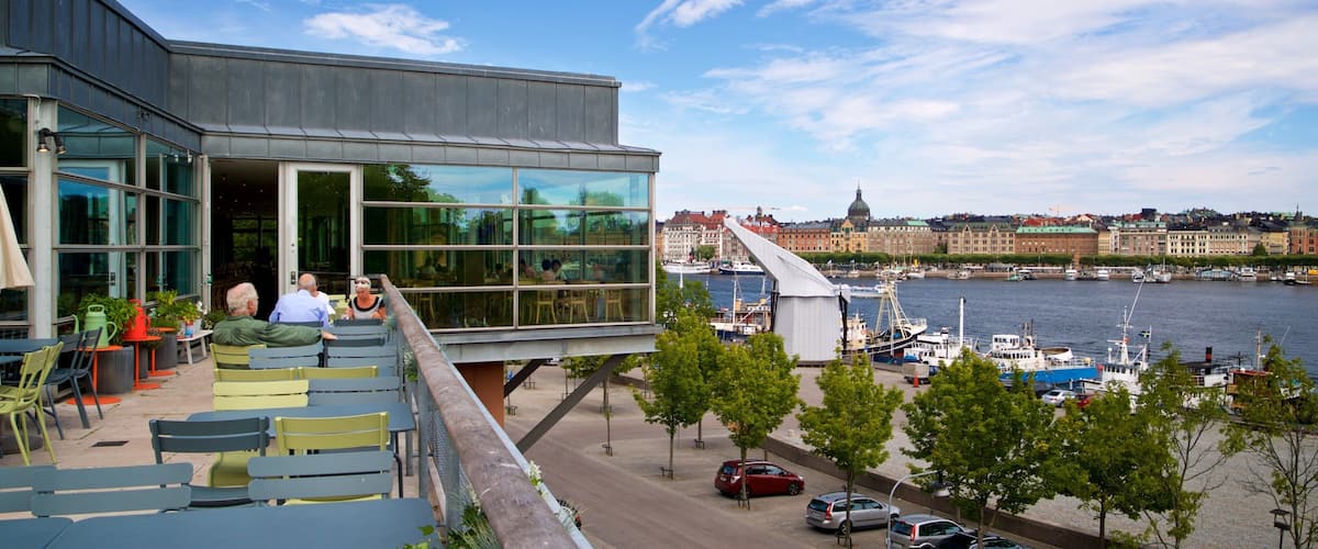 Museum of Modern Art featuring a bay or harbor and outdoor eating as well as a small group of people