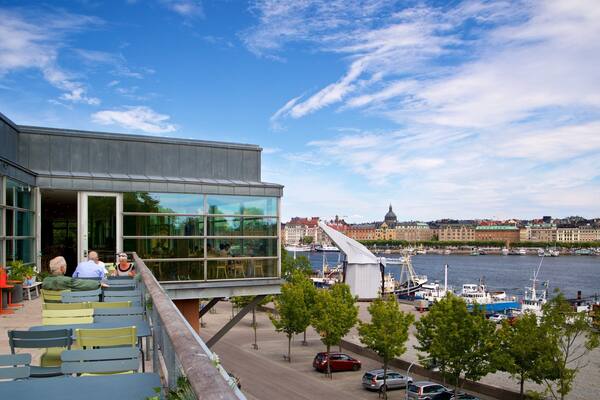 Museum of Modern Art featuring a bay or harbor and outdoor eating as well as a small group of people