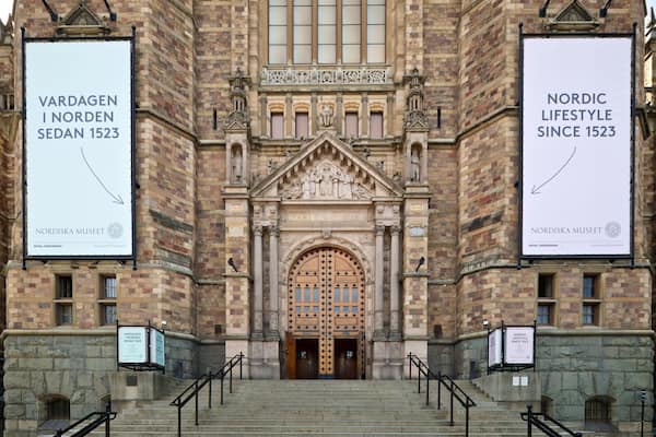 Der Eingang zum Nordiska Museum, mit aufwändiger Architektur und großen Bannern.