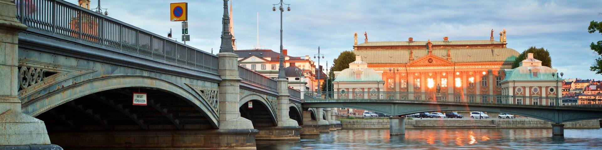 A bridge over a river with a reflection of lights on the water. There is a building with a dome and a sign that says "INFART FÖRBIUDEN" on the bridge.