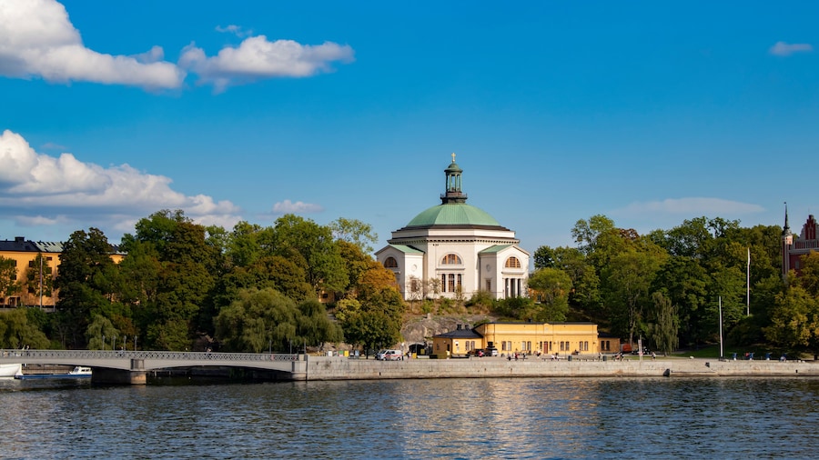 View of the Eric Ericsonhallen Concert Hall Surrounded by Trees rising from the Waterfront in Stockholm, Sweden