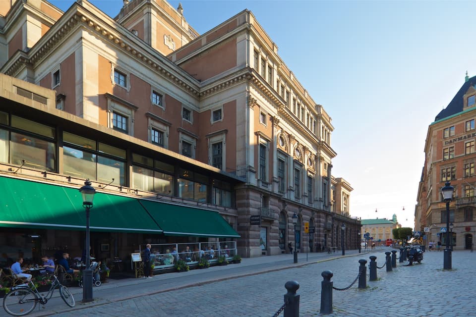A cobblestone street lined with historic buildings, a green awning, and a bicycle parked on the sidewalk.