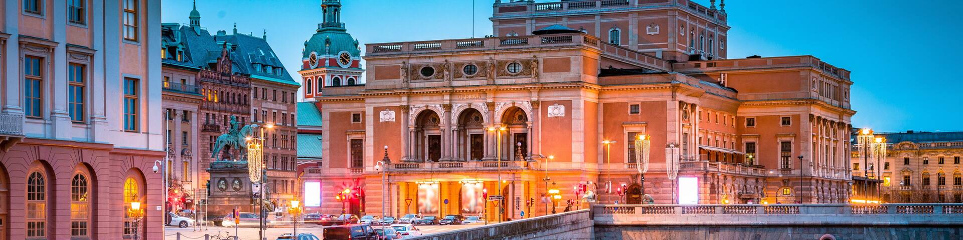 A historic bridge with arches, a river reflecting lights, and classical architecture in the background.