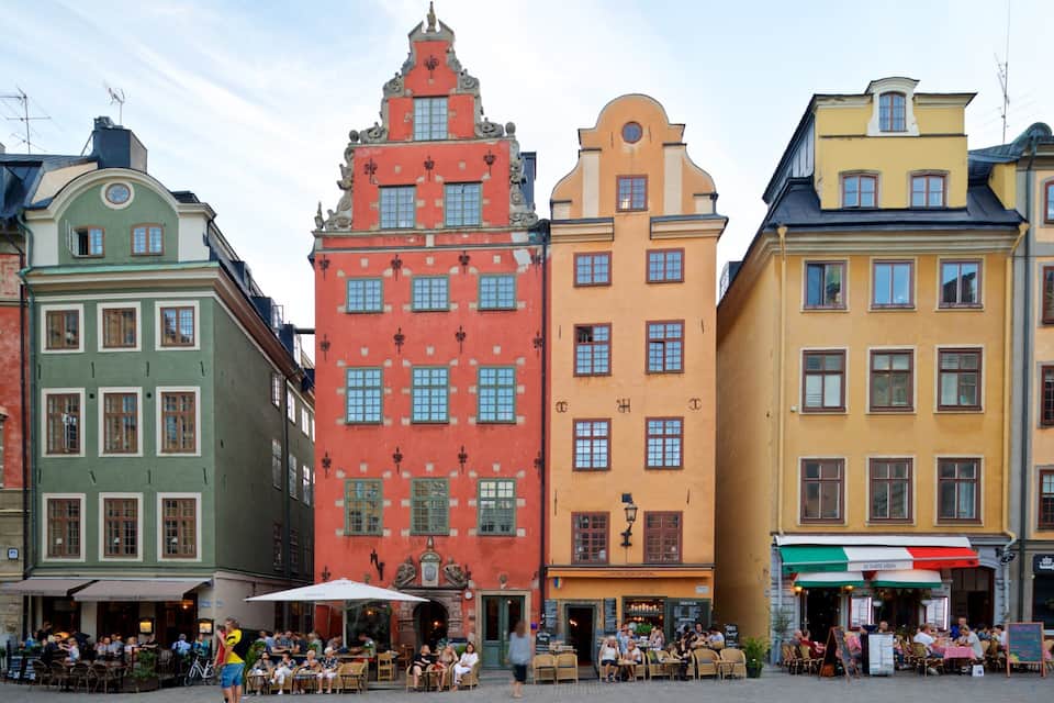 Una calle colorida con edificios históricos y cafés al aire libre.