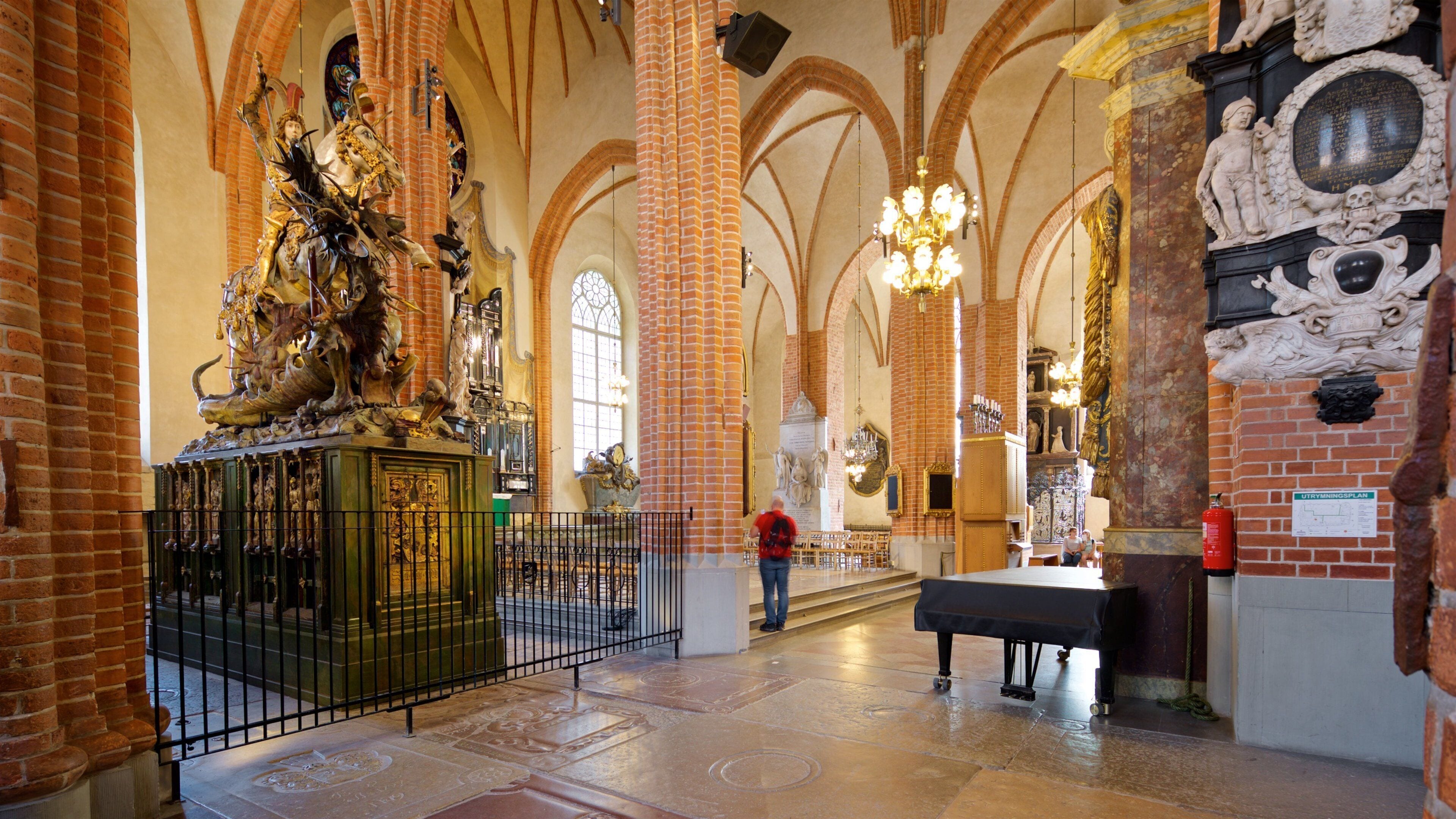 Interior imponente de una catedral, con altos techos abovedados, estatuas ricamente decoradas y una gran lámpara de cristal.