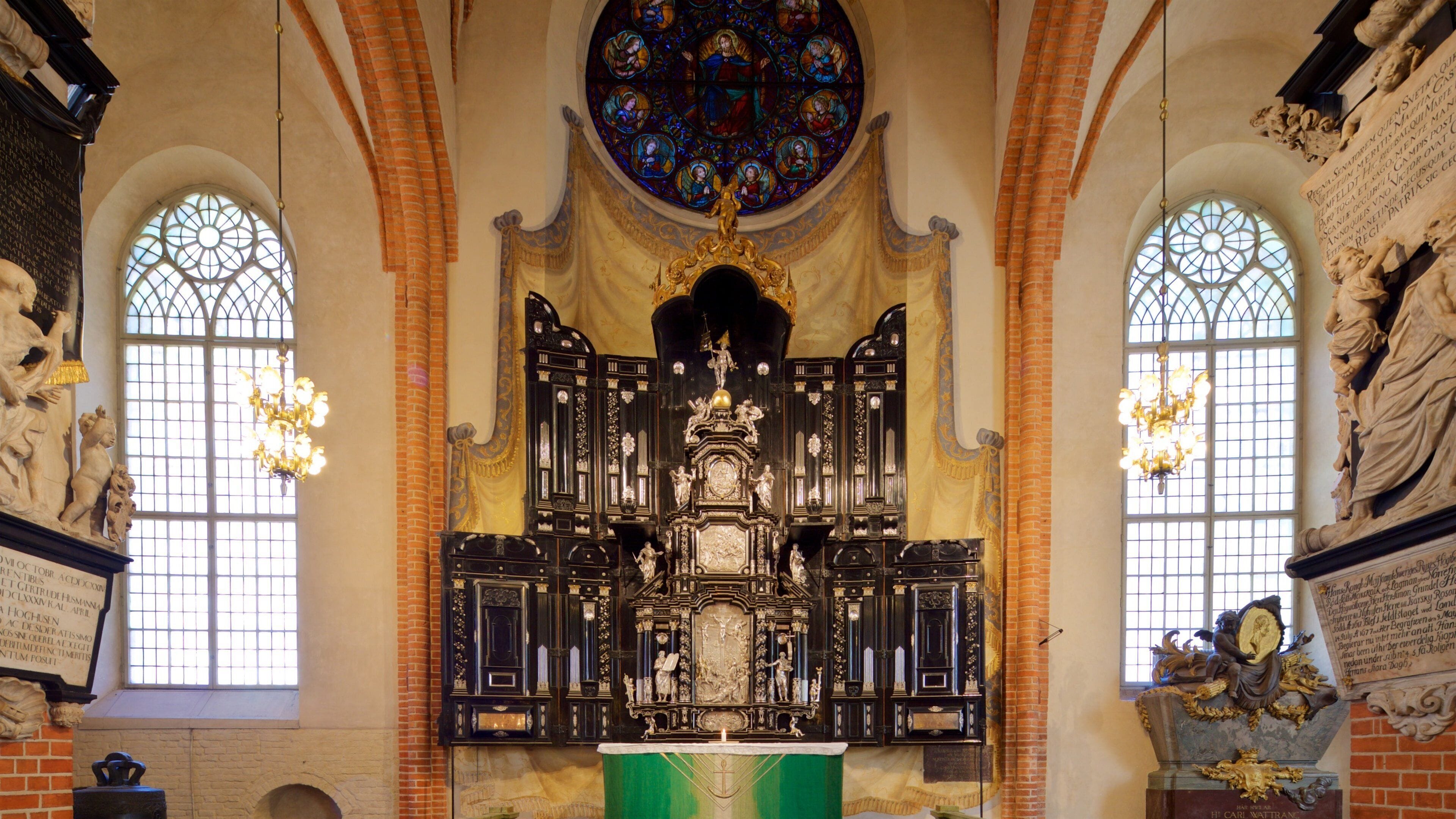 Interior de una iglesia ornamentada con un altar central, vidrieras y estatuas.