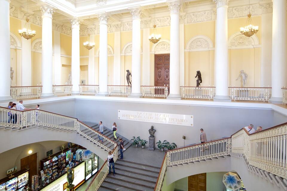 A grand interior with high ceilings, ornate columns, and a central staircase.