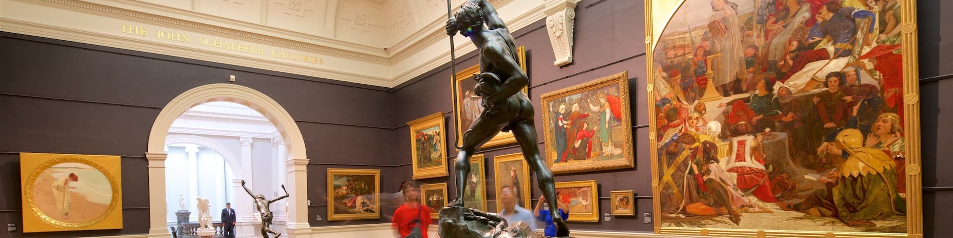 Interior de museo con esculturas clásicas, pinturas y un techo imponente.