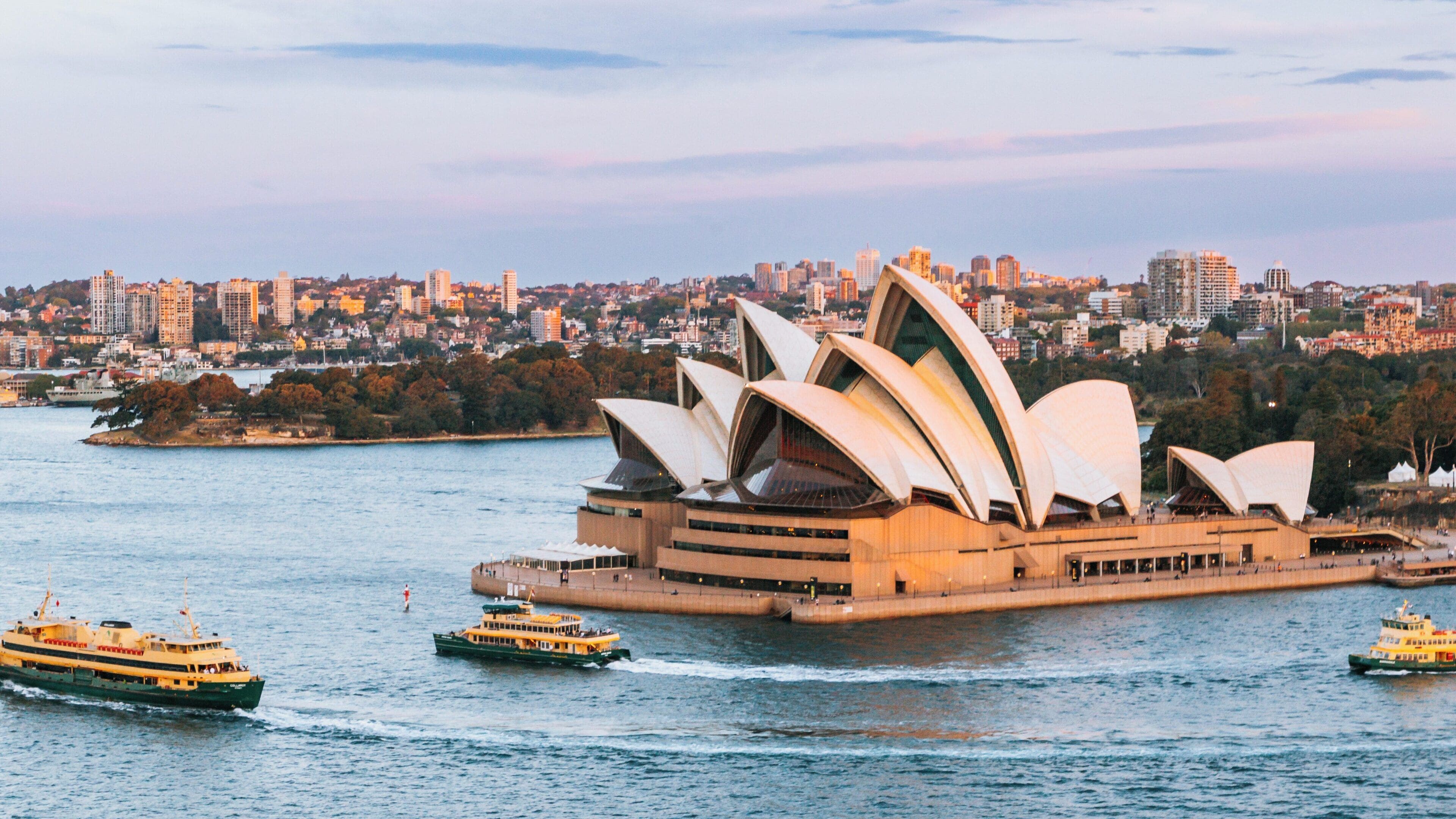 Sailing past Sydney Opera House in the bustling Central Business District during a vibrant evening light