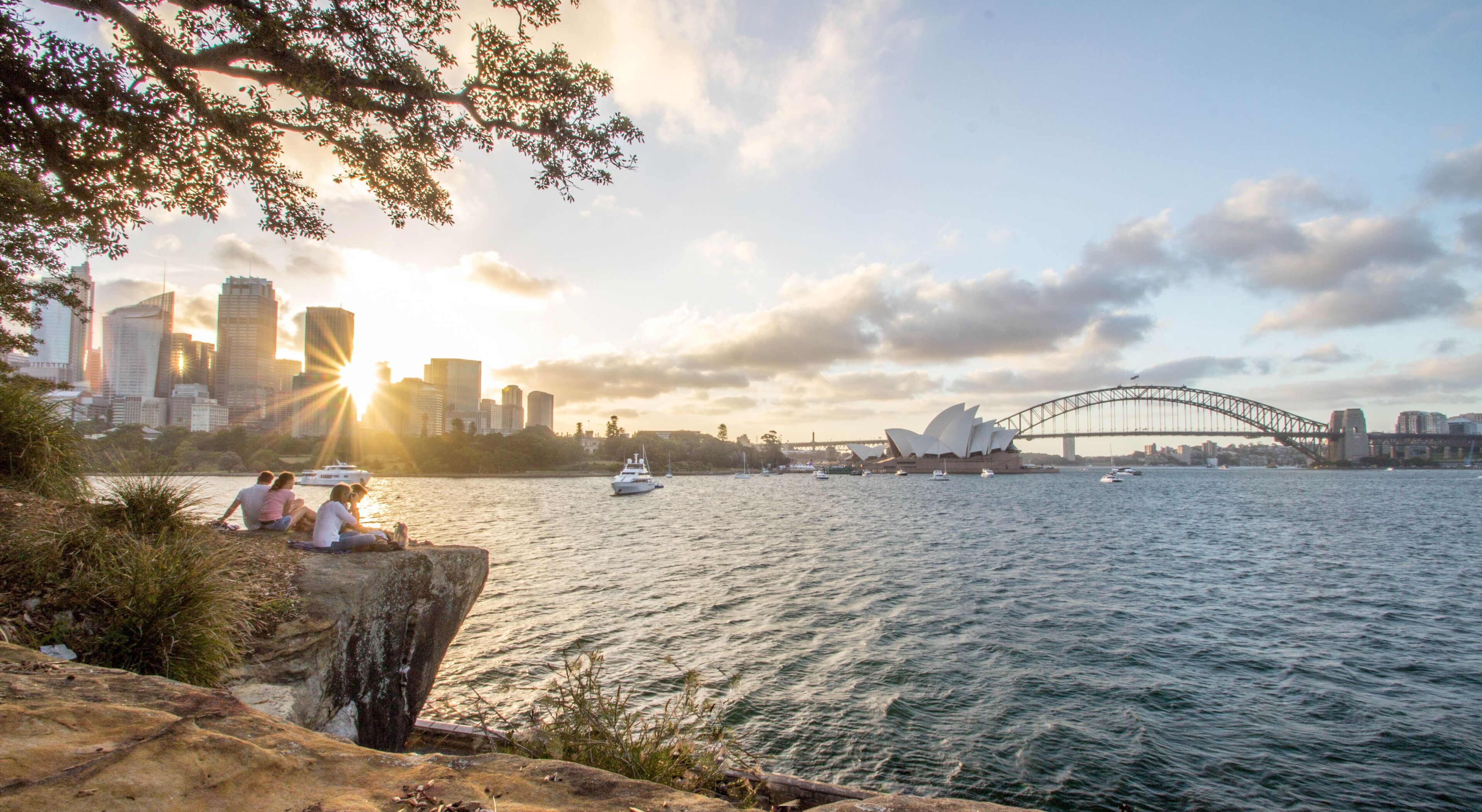 Paisagem urbana à beira-mar, com uma ponte imponente e a Ópera de Sydney.