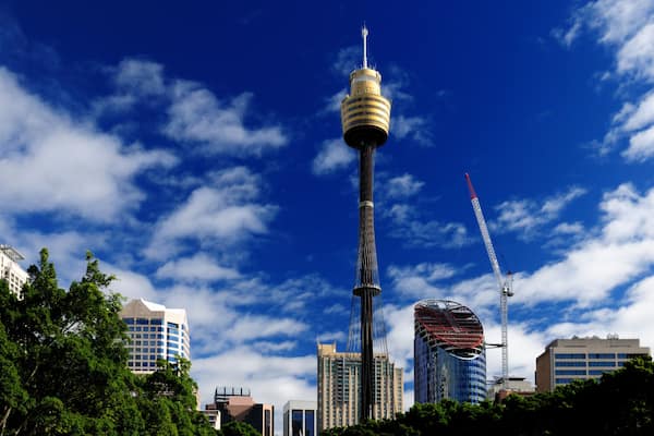A city skyline with a prominent tower, modern buildings, and a clear blue sky.
