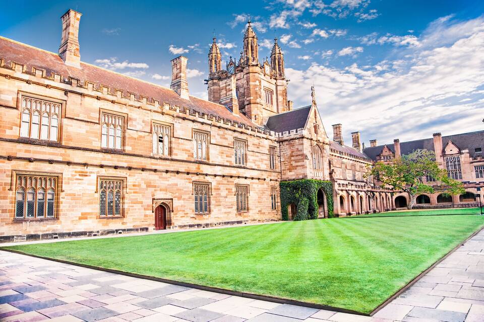 A historic building with arched windows and a large lawn.